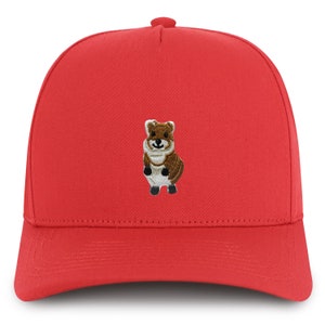 May include: A bright red baseball cap featuring an embroidered quokka design. The quokka is brown, white, and black. The cap has a curved brim and a button on top.