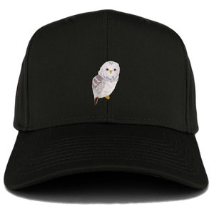 Op de afbeelding: Een zwarte baseballpet met een geborduurde witte uil op de voorkant.