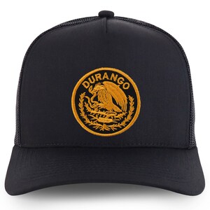 Könnte beinhalten: Schwarze Trucker-Kappe mit einem goldenen gestickten Logo, auf dem "DURANGO" steht und ein stilisierter Adler mit einer Schlange im Schnabel abgebildet ist.