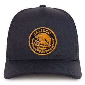 May include: A black trucker hat with a gold embroidered emblem featuring a stylized eagle and the word "JALISCO".