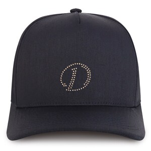 May include: A black baseball cap with a gold-colored circle logo featuring a stylized letter "J" in the center.