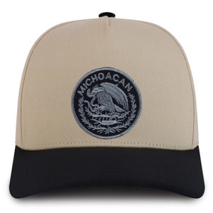 May include: A beige and black baseball cap with an embroidered patch featuring the coat of arms of Mexico and the text "MICHOACAN".