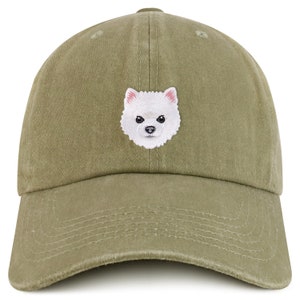 May include: A green baseball cap with an embroidered white Pomeranian dog on the front.