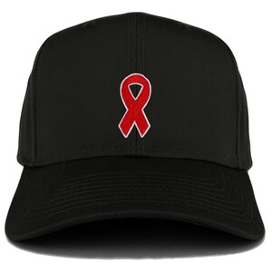 Peut inclure: Une casquette de baseball noire avec un ruban rouge brodé sur le devant.
