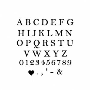 Puede incluir: Imagen en blanco y negro del alfabeto en letras may&uacute;sculas, los n&uacute;meros del 0 al 9 y signos de puntuaci&oacute;n, incluyendo un coraz&oacute;n, un punto, una coma, un ap&oacute;strofe, un guion y una ampersand.