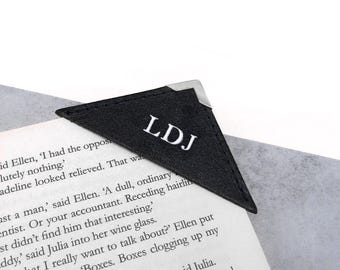 May include: Black leather bookmark with a silver metal corner and the initials "LDJ" embossed in white.