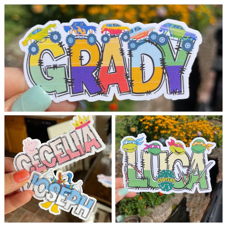 K&ouml;nnte beinhalten: Drei individuelle, konturgestanzte Aufkleber mit Namen und Figuren. Ein Aufkleber zeigt den Namen GRADY mit Monstertrucks. Ein weiterer zeigt CECELIA mit einer Krone und Peppa Wutz sowie JOSEPH mit Donald Duck. Der dritte zeigt LUCA mit den Ninja Turtles.