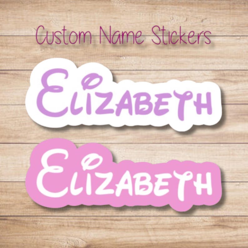 Peut inclure: Deux autocollants personnalis&eacute;s avec le nom "Elizabeth" dans une police fantaisiste. L'un est violet clair avec un bord blanc, l'autre rose avec un bord blanc. Le texte "Custom Name Stickers" est au-dessus.