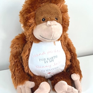 Peut inclure: Un singe en peluche marron avec un t-shirt blanc qui dit "Hand picked for earth by my Nanny Jo in heaven" avec un cœur rose.
