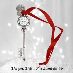 May include: Silver key-shaped Christmas ornament with a red ribbon. The key has a round charm with the text "Delta Phi Lambda" and a smaller charm with the text "Santa's Coming". The key also has the word "HOHOHO" engraved on the side.