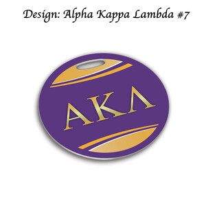 May include: Purple round keychain with a gold "AKA" logo and a gold stripe design.