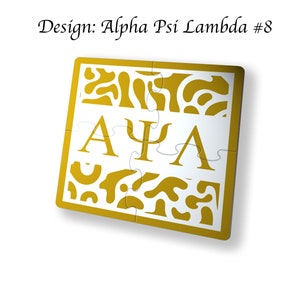 May include: A gold-colored puzzle piece with a white background. The puzzle piece features the Greek letters Alpha, Psi, and Lambda, forming the letters "AΨΛ".