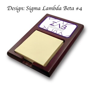 Może przedstawiać: Drewniany organizer biurkowy z blokiem samoprzylepnych karteczek i logo w kolorze fioletowym i białym z napisem "Sigma Lambda Beta International Fraternity".