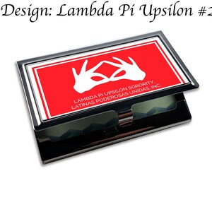 Könnte beinhalten: Ein silberner Visitenkartenhalter mit einem roten Einsatz, der das Symbol der Lambda Pi Upsilon Sorority und den Text "Lambda Pi Upsilon Sorority, Latinas Poderosas Unidas, Inc." zeigt.