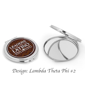 Può includere: Uno specchio compatto argentato con un design marrone e bianco con il testo "Leaders of the Latino Greek Movement".