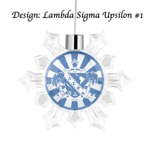 Op de afbeelding: Een blauwe en witte sneeuwvlok ornament met een Lambda Sigma Upsilon-wapen. Het wapen toont een schild met de Griekse letters Lambda, Sigma en Upsilon, samen met een palmboom en de woorden "Latinos Siempre Unidos".