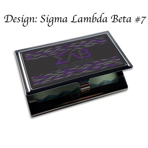 Könnte beinhalten: Ein schwarzer und silberner Visitenkartenhalter mit einem lila und grauen Design. Das Design zeigt die Buchstaben "ΣΛΒ" und den Text "Sigma Lambda Beta International Fraternity".