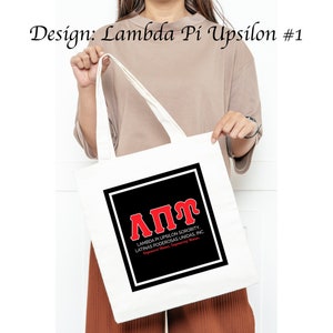 Op de afbeelding: Witte tote bag met een zwart vierkant met de rode letters "ΑΠΥ" en de tekst "Lambda Pi Upsilon Sorority, Latinas Poderosas Unidas, Inc."