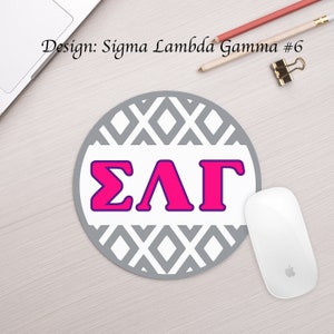 May include: A round gray mouse pad with a white and gray geometric pattern. The letters "ΣΛΓ" are in pink with a purple outline in the center of the mouse pad.