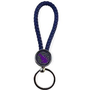 May include: A navy blue braided leather keychain with a silver key ring. The keychain features a round emblem with a purple silhouette of a dog on a gray and white leopard print background. The text "Design: Sigma Lambda Gamma #2" is at the bottom.