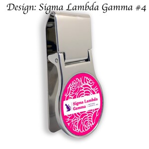 Könnte beinhalten: Ein silberner Geldclip mit einem runden, rosafarbenen, floralen Design. Das Design zeigt eine weiße Umrandung von Rosen und den Text "Sigma Lambda Gamma National Sorority, Inc."