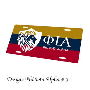 以下が含まれることがあります： 金、ネイビーブルー、赤色の長方形ナンバープレート。デザインには、ライオンの頭と白い文字「ΦΙΑ」が入った白いシールドが含まれています。「PHI IOTA ALPHA」の文字が下にあります。