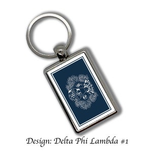 May include: A silver keychain with a rectangular blue and white enamel charm featuring a white design of a Greek fraternity symbol. The text "Design: Delta Phi Lambda #1" is below the image.