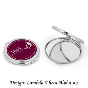May include: A silver compact mirror with a burgundy lid featuring the Greek letters "ΛΘΑ" and the text "Lambda Theta Alpha,  Latin Sorority, Incorporated".