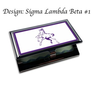 Puede incluir: Un porta tarjetas de visita plateado con un borde morado y un fondo blanco. El porta tarjetas presenta una silueta de caballo morado en la parte delantera. El texto "Design: Sigma Lambda Beta #1" es visible sobre el porta tarjetas.