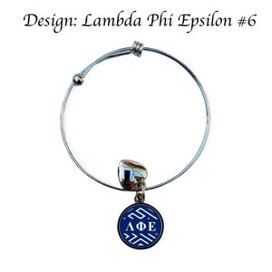 May include: A silver expandable bracelet with a blue and white charm featuring the Greek letters "&Lambda;&Phi;&Epsilon;" in white. The charm is round and has a white geometric pattern.