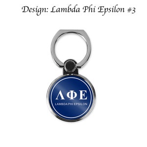 May include: A silver phone ring holder with a blue circle featuring the Greek letters Lambda Phi Epsilon and the text "Lambda Phi Epsilon" in white.