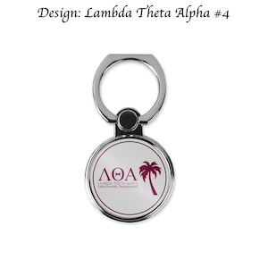 May include: A silver phone ring holder with a white circle featuring a pink palm tree and the text "ΛΘΑ LAMBDA THETA ALPHA Latin Sorority, Incorporated".