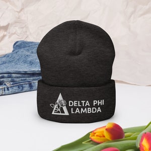Könnte beinhalten: Eine schwarze Mütze mit einem weißen gestickten Dreieck, einer Rose und dem Text "Delta Phi Lambda".