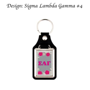 May include: Black leather keychain with a silver-colored rectangular pendant. The pendant has a gray background with the Greek letters ΣΛΓ in pink. Pink roses and white floral accents surround the letters. The text "Design: Sigma Lambda Gamma #4" is at the top.