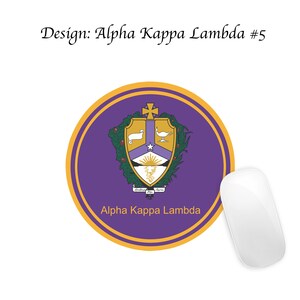 Pode incluir: Um mousepad redondo roxo e dourado com o bras&atilde;o do Alpha Kappa Lambda e as palavras "Alpha Kappa Lambda" impressas nele.