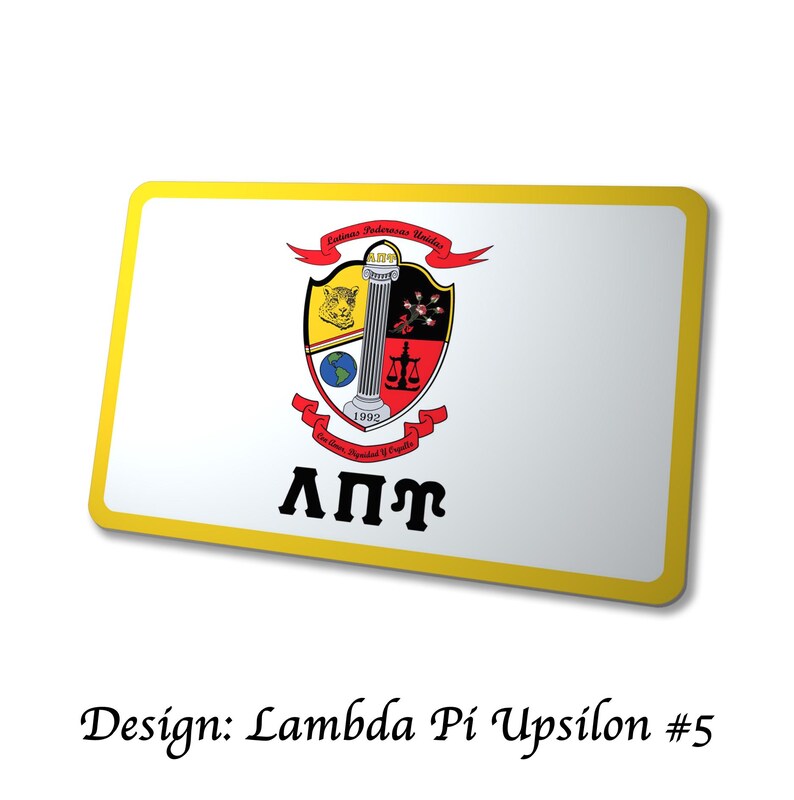 Op de afbeelding: Een rechthoekige witte badge met een gele rand toont een wapen met een zuil, weegschaal en een wereldbol. Het wapen staat boven de Griekse letters &Lambda;&Pi;&Gamma;. De badge bevat ook de tekst "Design: Lambda Pi Upsilon #5".
