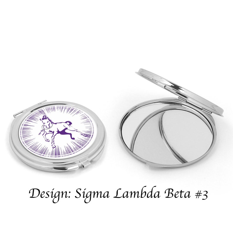 Pu&ograve; includere: Uno specchio compatto argentato con un design di cavallo viola e bianco. Il design include il testo "Sigma Lambda Beta #3".