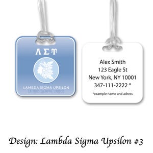 Op de afbeelding: Twee bagagelabels. Eén is lichtblauw met witte tekst en een cirkelvormig embleem. De andere is wit met zwarte tekst. Beide labels hebben een doorzichtige plastic lus voor bevestiging. De tekst op het blauwe label luidt "Lambda Sigma Upsilon Latinos Siempre Unidos."