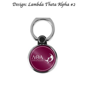 Op de afbeelding: Een zilveren telefoonringhouder met een ronde, donkerrode schijf met een wit Grieks letterontwerp en de tekst "&Lambda;&Theta;&Alpha; LAMBDA THETA ALPHA Latin Sorority, Incorporated".