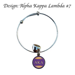 Puede incluir: Un brazalete extensible de plata con un dije morado y dorado con las letras "AKL".