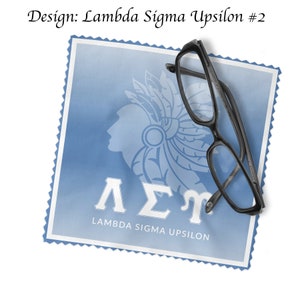 May include: A blue and white fabric cleaning cloth with the Greek letters Lambda Sigma Upsilon and the words "Lambda Sigma Upsilon" printed on it. A pair of black eyeglasses is lying on top of the cloth.