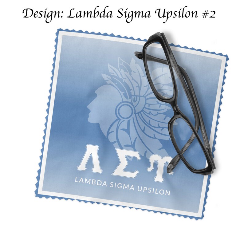 May include: A blue and white fabric cleaning cloth with the Greek letters Lambda Sigma Upsilon and the words "Lambda Sigma Upsilon" printed on it. A pair of black eyeglasses is lying on top of the cloth.