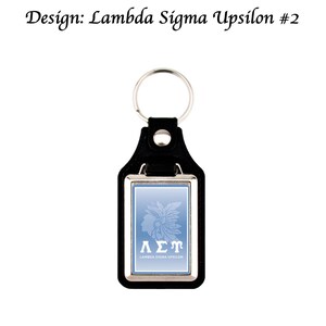 May include: Black leather keychain with a silver-coloured metal frame and key ring. The light blue insert features a Native American profile and the Greek letters &Lambda;&Sigma;&Upsilon;, with the text "LAMBDA SIGMA UPSILON" below.