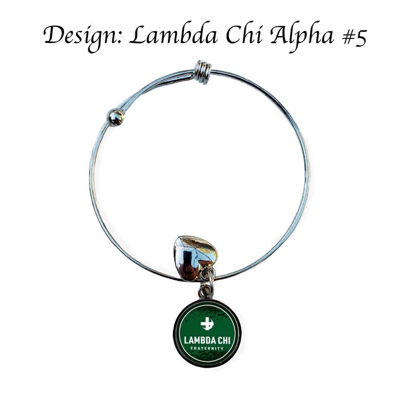 Puede incluir: Un brazalete extensible de plata con un dije verde que dice "Lambda Chi Fraternity" con una cruz blanca.