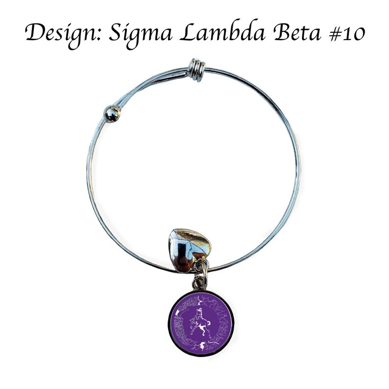 K&ouml;nnte beinhalten: Ein silbernes, ausziehbares Armband mit einem violetten Anh&auml;nger, der ein wei&szlig;es griechisches Buchstaben-Design zeigt. Der Anh&auml;nger ist rund und hat einen wei&szlig;en Rand. Das Armband ist mit "Design: Sigma Lambda Beta #10" beschriftet.