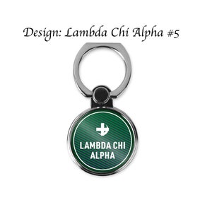 May include: A silver phone ring holder with a green and blue circle. The circle has a white cross and the text "Lambda Chi Alpha".