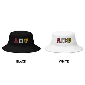 May include: Two bucket hats, one black and one white, with the letters "A&Pi;&Pi;&Gamma;" embroidered in red, white, and gold.