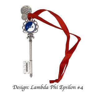 May include: A silver key-shaped ornament with a blue and white circle featuring the letters "ΑΦΕ" and the words "HOHOHO" on the bottom. The ornament is attached to a red ribbon.
