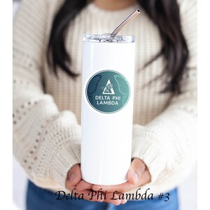 May include: White stainless steel tumbler with a teal and green sticker featuring a butterfly, a triangle, and the text "Delta Phi Lambda".