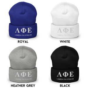 Puede incluir: Cuatro gorros de lana de diferentes colores con las letras griegas "&Lambda;&Phi;&Epsilon;" y las palabras "Lambda Phi Epsilon" bordadas en blanco en la parte delantera de cada gorro. Los gorros son de color azul real, blanco, gris jaspeado y negro.